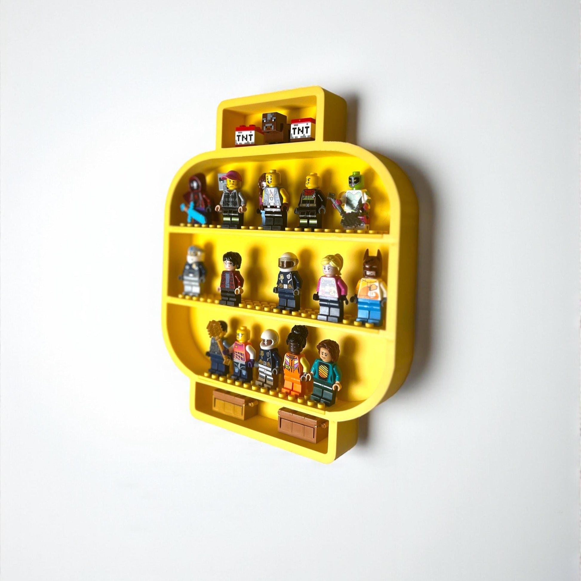 Yellow LEGO minifigure head shelf mounted on a wall in a child’s room, used as storage for minifigures and small collectibles.