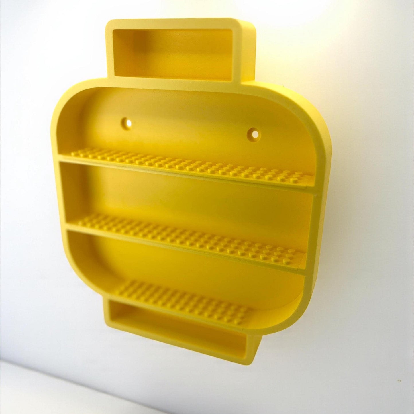 Angled perspective of yellow LEGO-inspired display shelf showing depth and inner compartments.